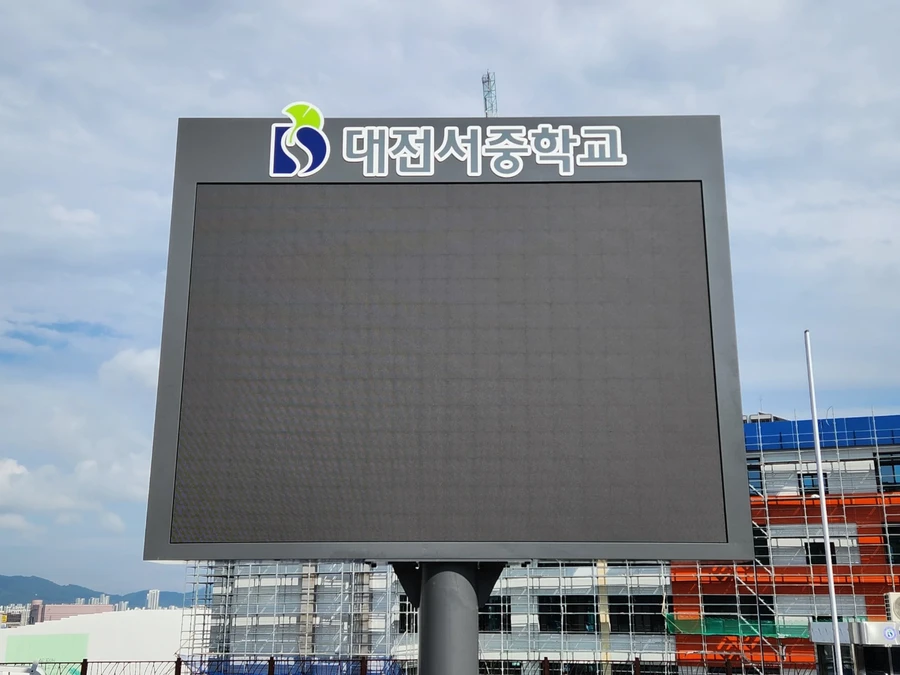 교문 인근에서 기둥 위에 올려진 학교 로고가 있는 소형 LED 전광판을 가까이서 본 모습