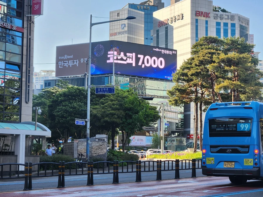 강남 전광판 업체 상담 참고 - 도로변 건물 상단에 설치된 가로형 LED 전광판과 가로등